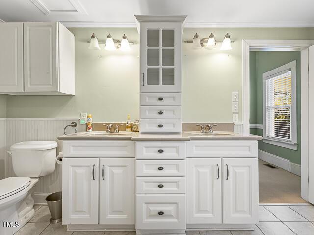 715 E Broad St, Fuquay Varina, NC 27526 - full bathroom with tile patterned flooring, double vanity, toilet, ornamental molding, and a wainscoted wall