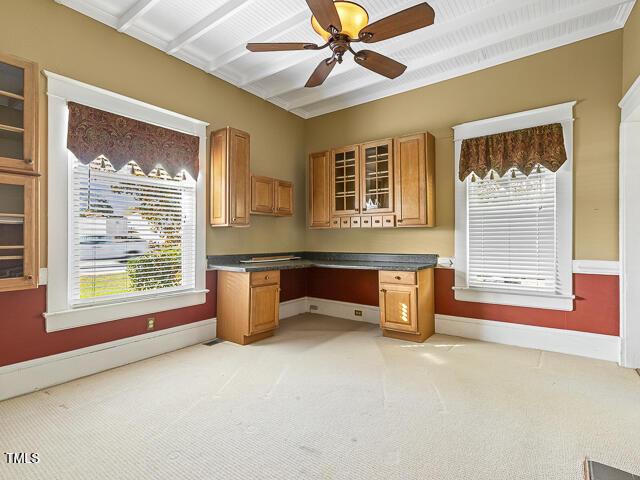 715 E Broad St, Fuquay Varina, NC 27526 - unfurnished office with baseboards, built in desk, ceiling fan, light colored carpet, and plenty of natural light