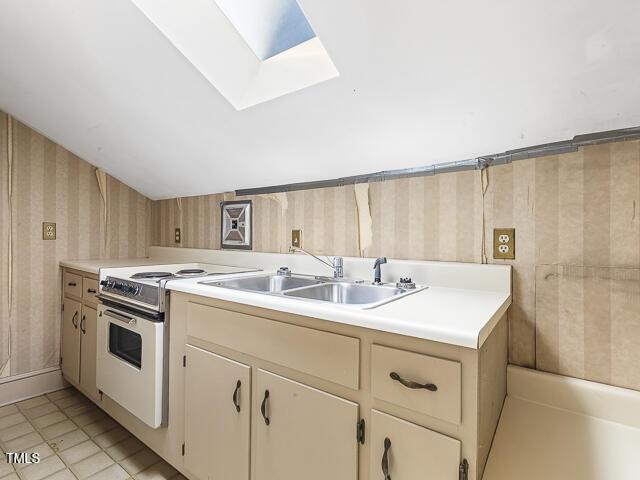 715 E Broad St, Fuquay Varina, NC 27526 - kitchen featuring electric range, wallpapered walls, a skylight, light countertops, and a sink
