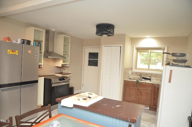 kitchen featuring sink, wall chimney exhaust hood, backsplash, stainless steel appliances, and light stone countertops