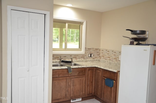 kitchen featuring backsplash, white refrigerator, and sink