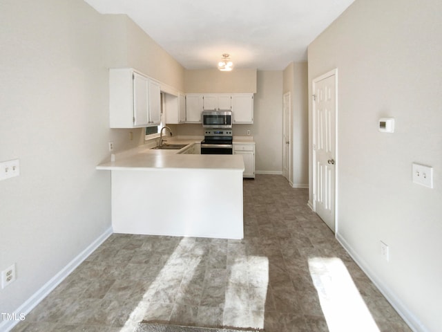 kitchen with kitchen peninsula, sink, appliances with stainless steel finishes, and white cabinetry