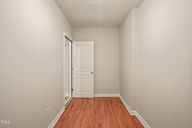 corridor featuring light hardwood / wood-style flooring and a textured ceiling