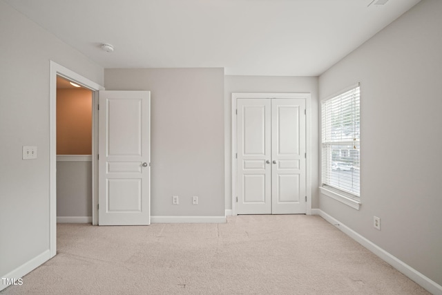 unfurnished bedroom with a closet and light colored carpet