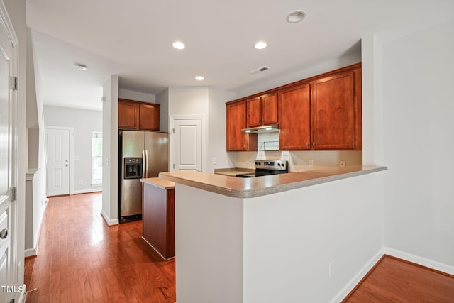 kitchen with stainless steel appliances, kitchen peninsula, and dark hardwood / wood-style flooring