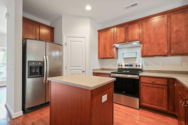 kitchen with stainless steel appliances, light hardwood / wood-style floors, decorative backsplash, and a center island