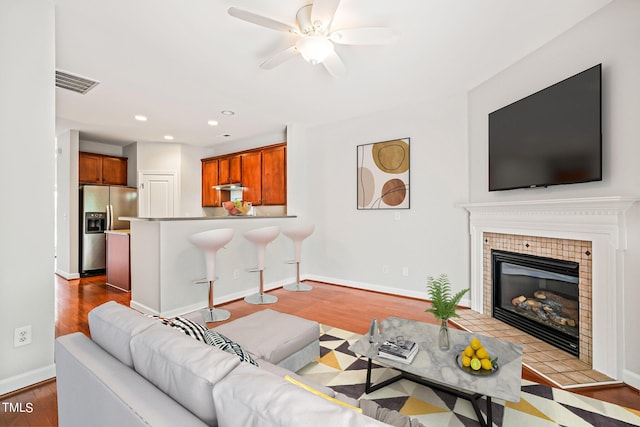 living room with a fireplace, ceiling fan, and light hardwood / wood-style flooring