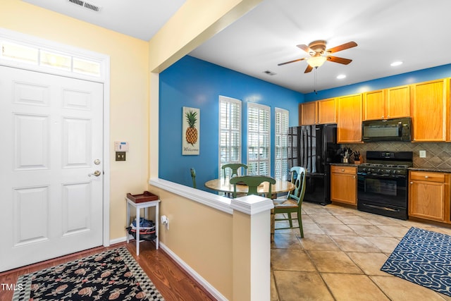 kitchen featuring light wood-type flooring, black appliances, backsplash, and ceiling fan