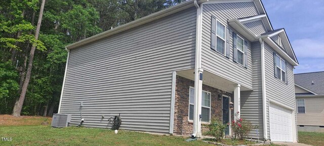 view of side of property featuring central AC, a lawn, and a garage