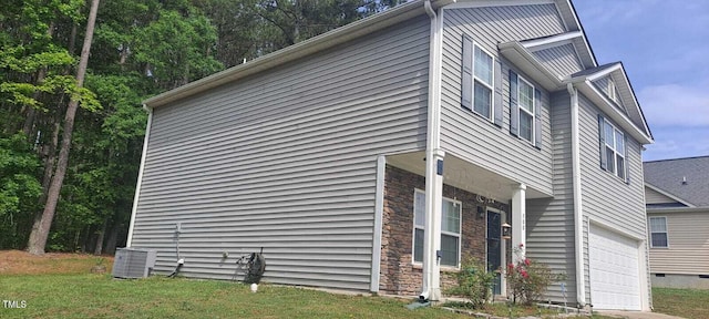 view of home's exterior featuring a yard, stone siding, central air condition unit, and a garage