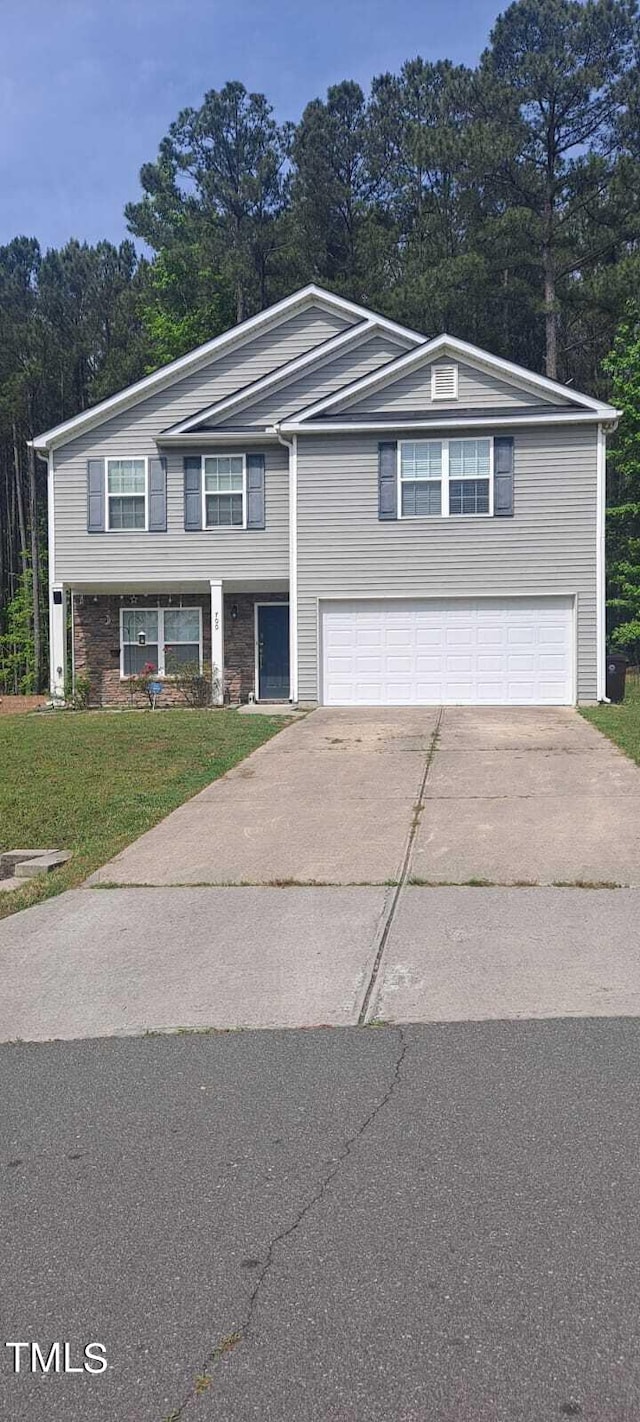 view of front of house with a garage, concrete driveway, and a front lawn
