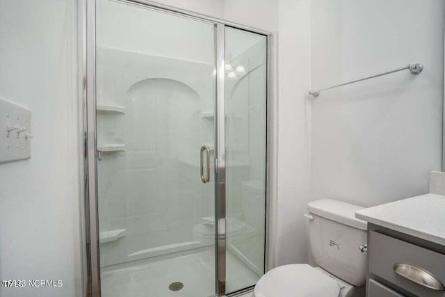 bathroom with vanity, toilet, and a shower with shower door