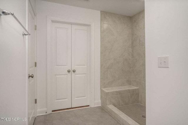 bathroom featuring tiled shower and tile patterned flooring