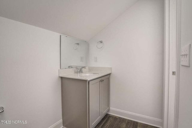 bathroom featuring hardwood / wood-style floors, vaulted ceiling, and vanity