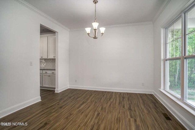 unfurnished room with crown molding, a healthy amount of sunlight, a chandelier, and dark wood-type flooring