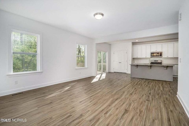 unfurnished living room featuring hardwood / wood-style floors and plenty of natural light