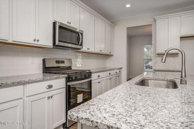 kitchen featuring white cabinets, light stone counters, and stainless steel appliances