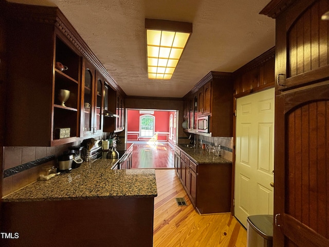 kitchen featuring light wood-type flooring, kitchen peninsula, sink, and tasteful backsplash