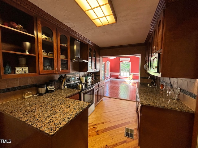 kitchen featuring crown molding, appliances with stainless steel finishes, light wood-type flooring, and wall chimney range hood