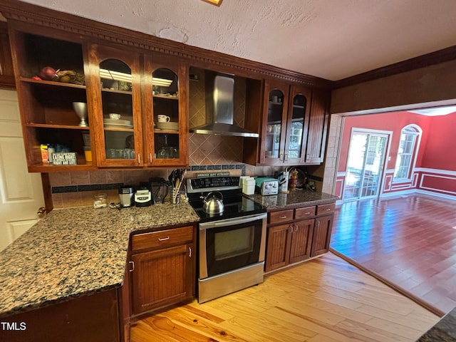 kitchen featuring wall chimney range hood, tasteful backsplash, stainless steel electric range oven, and light hardwood / wood-style flooring