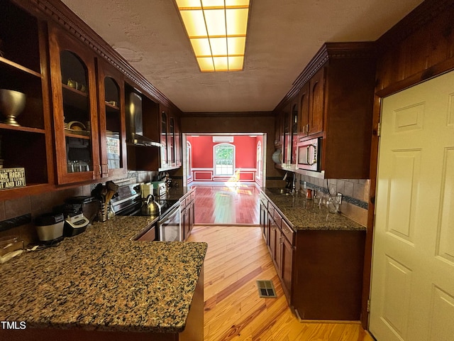 kitchen featuring light wood-type flooring, dark stone countertops, sink, and stainless steel appliances