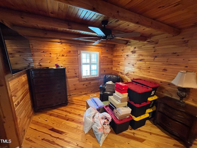 living area with ceiling fan, a skylight, light hardwood / wood-style floors, and beam ceiling