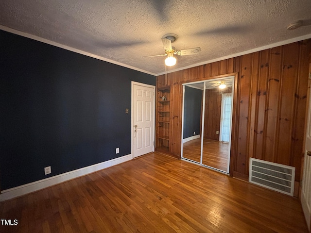 unfurnished bedroom with a textured ceiling, ornamental molding, ceiling fan, and hardwood / wood-style flooring