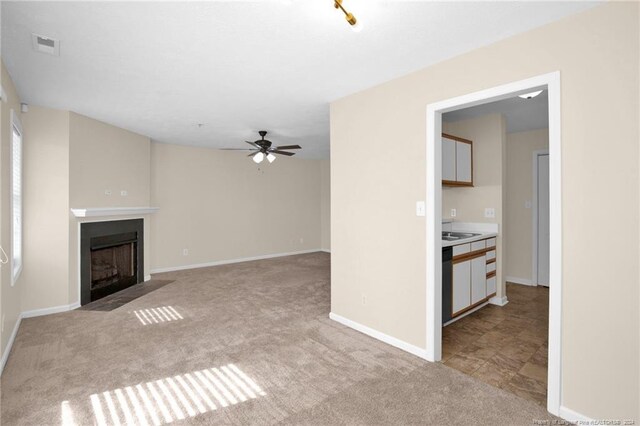 unfurnished living room with ceiling fan and light carpet