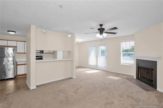 kitchen with appliances with stainless steel finishes, light colored carpet, white cabinetry, and ceiling fan