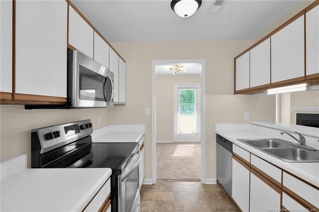 kitchen with light colored carpet, sink, appliances with stainless steel finishes, and white cabinetry