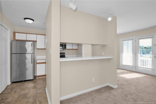 kitchen featuring white cabinets, stainless steel appliances, and light carpet