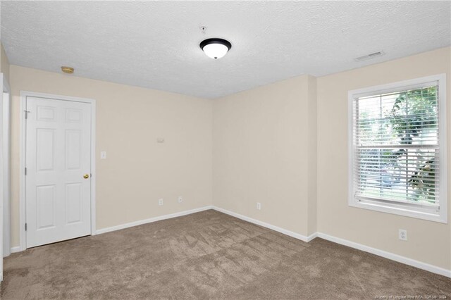 unfurnished room featuring carpet flooring and a textured ceiling