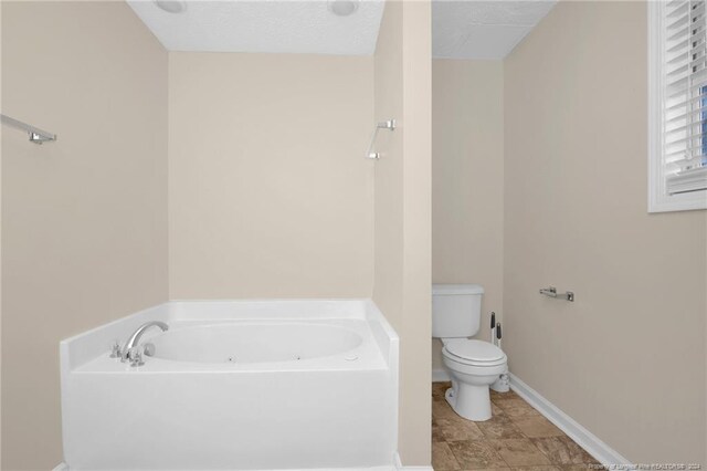 bathroom featuring toilet, a bathing tub, and a textured ceiling