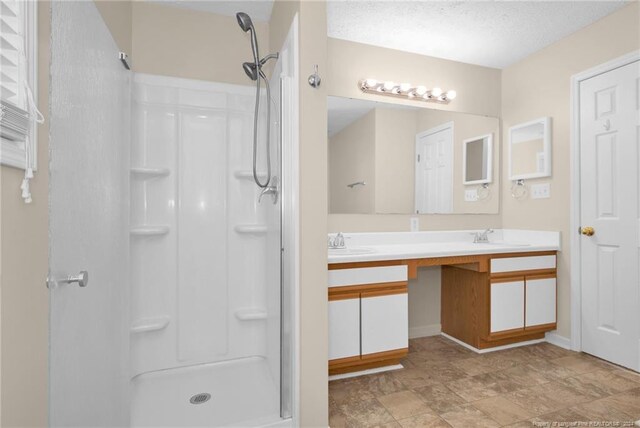 bathroom featuring walk in shower, a textured ceiling, and vanity