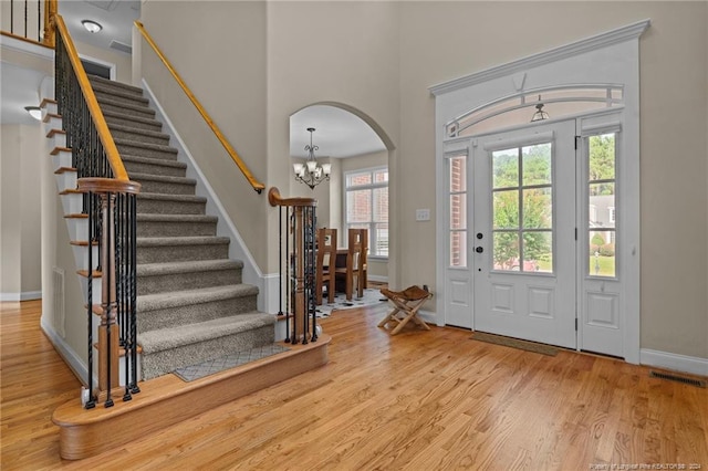 entryway featuring a high ceiling, an inviting chandelier, and light hardwood / wood-style floors