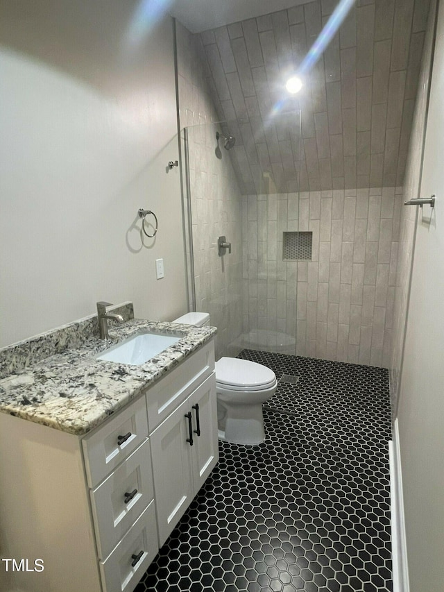 bathroom with tiled shower, vanity, toilet, and tile patterned floors