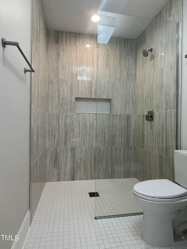 bathroom featuring tiled shower, toilet, and tile patterned floors