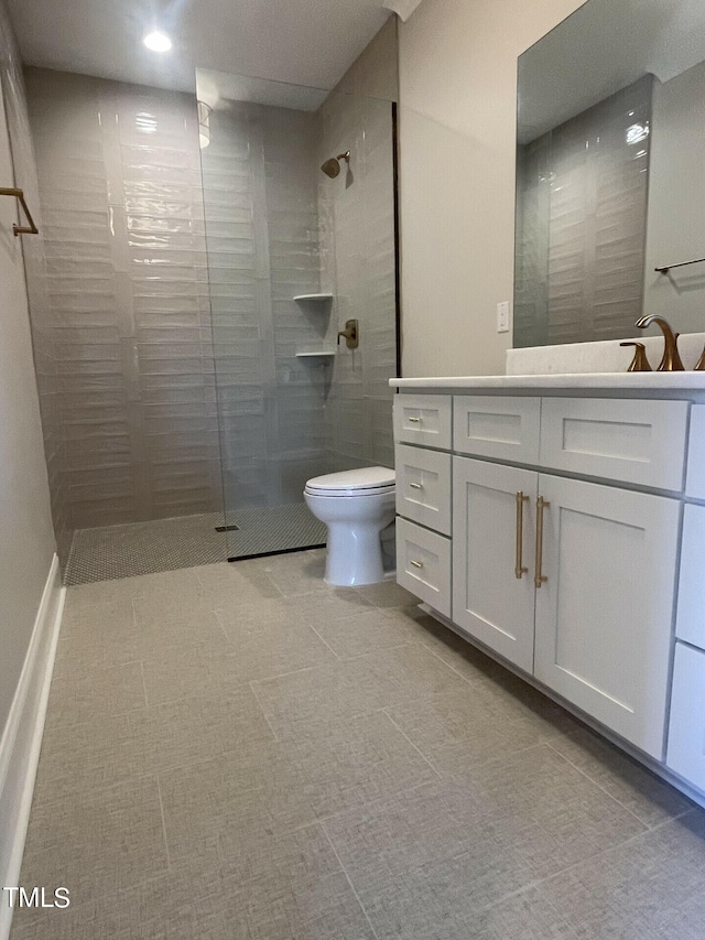 bathroom with vanity, toilet, and a tile shower