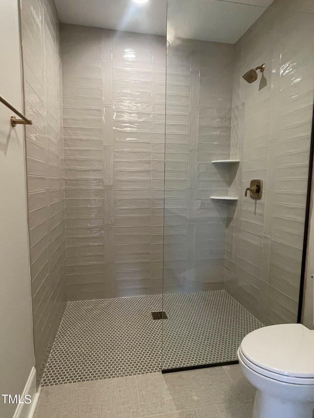 bathroom featuring tiled shower, toilet, and tile patterned floors