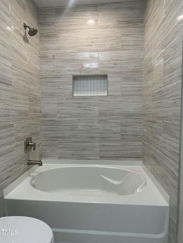 bathroom featuring toilet and tiled shower / bath combo