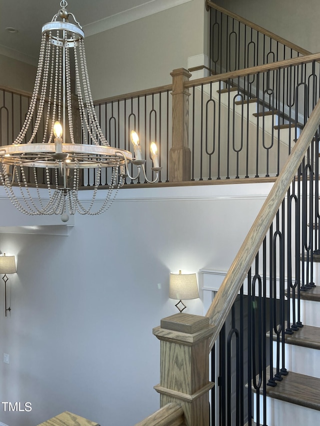 stairway with hardwood / wood-style floors, a notable chandelier, and ornamental molding