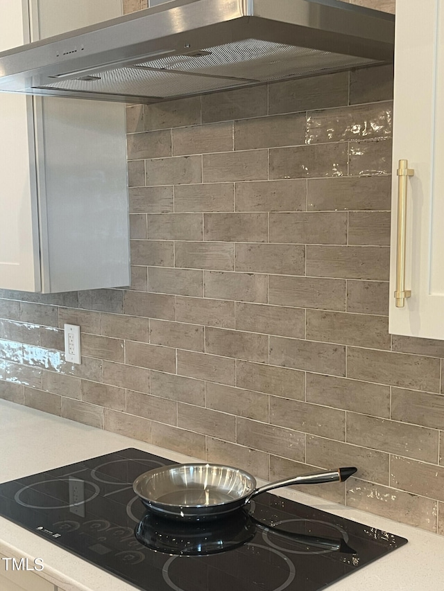 kitchen featuring ventilation hood, black electric cooktop, and white cabinets