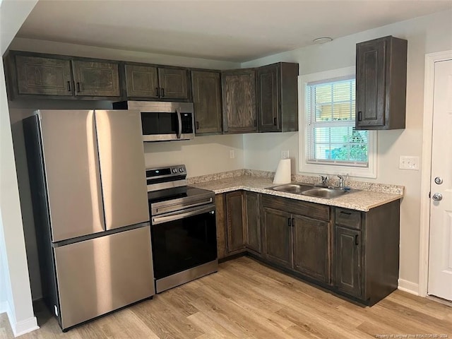 kitchen with sink, appliances with stainless steel finishes, dark brown cabinets, and light hardwood / wood-style floors