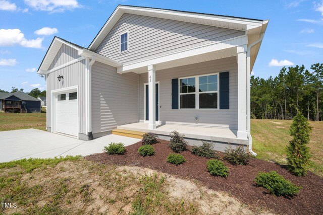 view of front of home featuring a front yard, a garage, and a porch