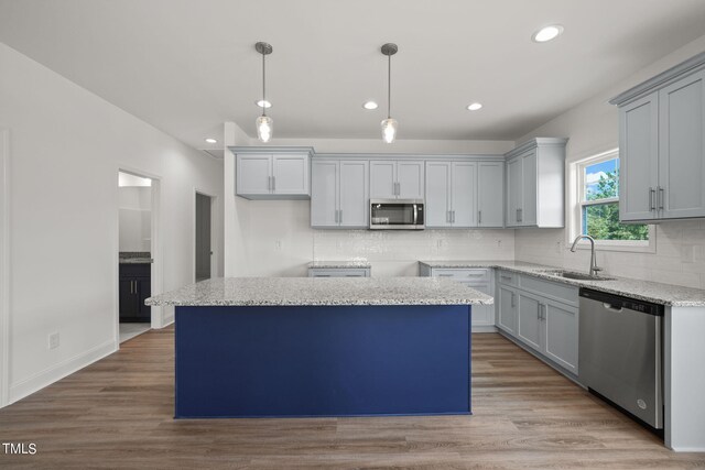 kitchen with light hardwood / wood-style flooring, a center island, stainless steel appliances, and sink