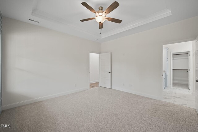 carpeted empty room with a tray ceiling, ornamental molding, and ceiling fan