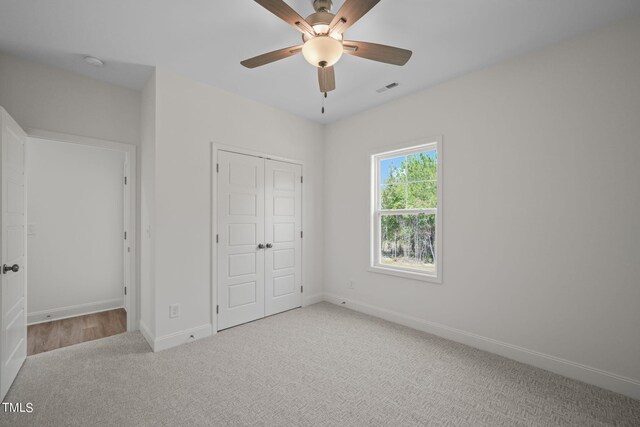 unfurnished bedroom featuring light colored carpet, ceiling fan, and a closet