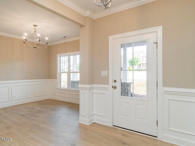 doorway to outside with ornamental molding, a chandelier, and light hardwood / wood-style floors