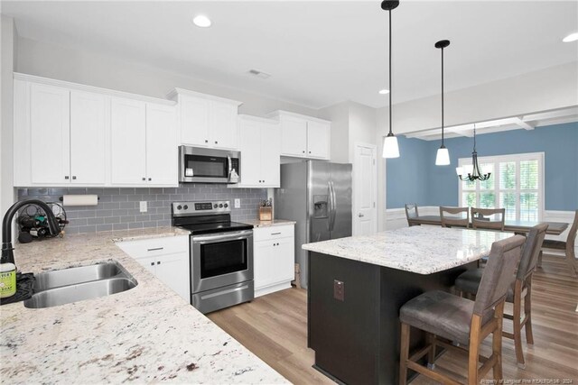 kitchen with a kitchen island, light wood-type flooring, sink, and appliances with stainless steel finishes