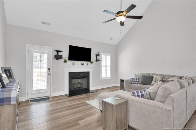 living room featuring high vaulted ceiling, ceiling fan, plenty of natural light, and wood-type flooring